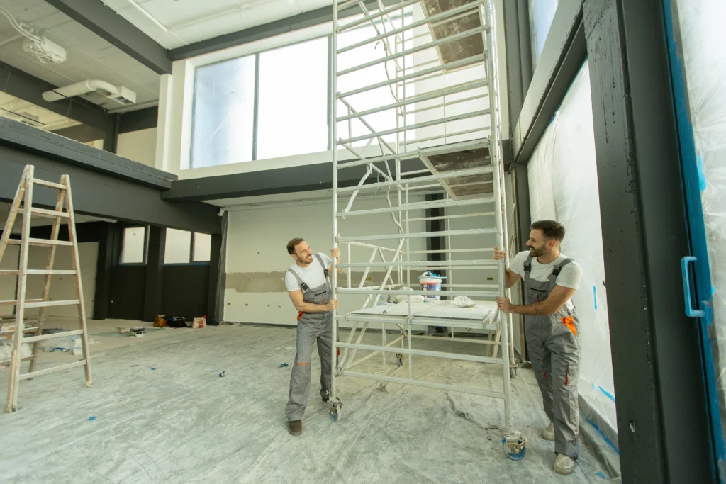 Deux ouvriers en train de manipuler un échafaudage roulant sur un chantier intérieur – formation travaux en hauteur et utilisation des EPI